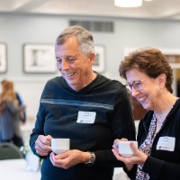 Gary & Kathy Crandall smiling at picture board while holding mugs